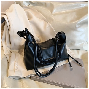 Close-up of black crossbody bag featuring pleated flap and metallic silver strap details