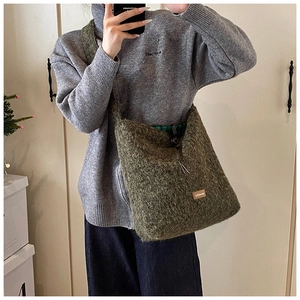 Détail d'un sac cabas en peluche vert olive avec étiquette brune et tissu texturé