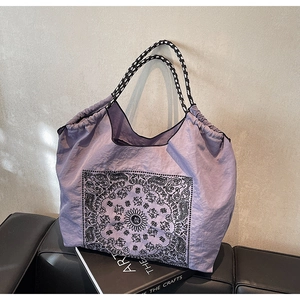 Detail of lavender paisley tote bag with checkered strap on an art book in a modern setting