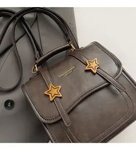 Detail of vintage brown leather handbag with gold star buckles and embossed fashion logo