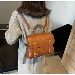Brown vintage faux leather backpack shown on shoulder with gold-tone hardware details
