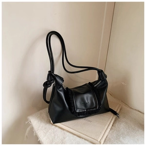 Detail of black crossbody bag featuring soft leather texture and elegant pleated ruffles