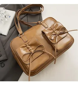 Detail of vintage brown PU leather handbag featuring decorative bow pockets and shiny finish