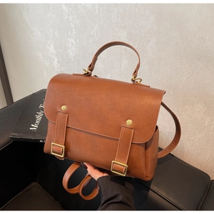 Detail of vintage brown leather backpack showing gold buckles and textured finish