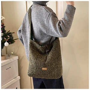 Détail du sac cabas en peluche vert foncé avec écusson marron et bandoulière large