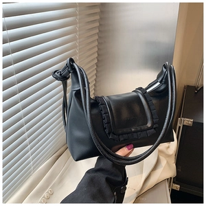 Detail of black leather hobo bag featuring elegant ruffle trim and twisted shoulder strap
