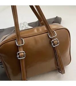 Close-up of retro brown leather Boston bag with white stitching and silver hardware detail