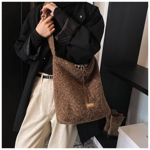 Détail de la texture en peluche marron du sac avec étiquette en cuir et cordon