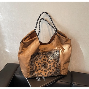 Detail of vintage tote bag with black paisley patterns and woven shoulder straps