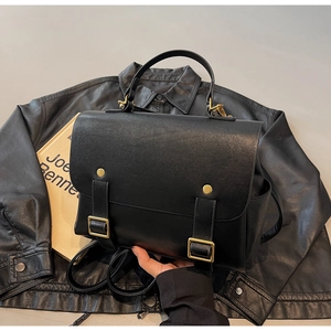 Detailed close-up of retro black leather backpack with premium gold metal hardware buckles