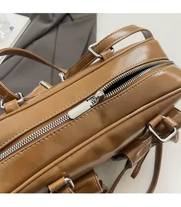 Detail of smooth silver metal zipper and white contrast stitching on brown leather bag