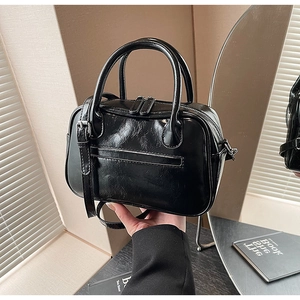 Detail of black pleated texture handbag with dual zippers and adjustable shoulder strap