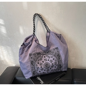 Detail of purple paisley tote bag with drawstring closure and braided cord handle