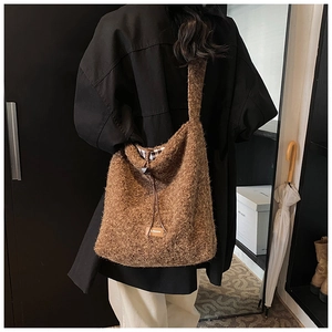 Détail d'un sac cabas marron en peluche avec cordon et doublure à carreaux porté