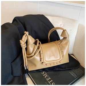 Detail of camel leather handbag featuring ruffled flap and unique knotted top handle design
