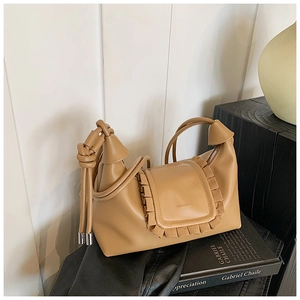 Detailed macro view of khaki leather handbag with ruffled edges and fringe tassel accents