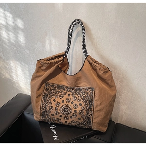 Detail of vintage paisley tote bag with drawstring closure on leather sofa