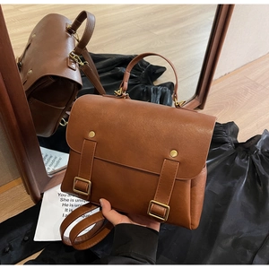 Close-up of vintage brown leather backpack with gold metal buckles and top handle grip
