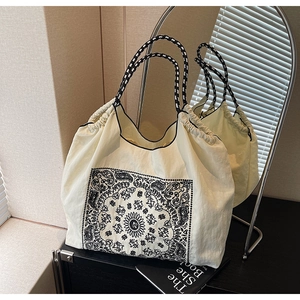 Close-up of beige drawstring tote bag with vintage paisley pattern and woven strap
