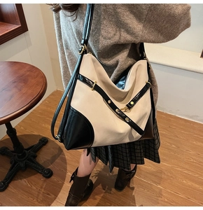 Close-up of cream and black large shoulder bag with gold metal buckle detail