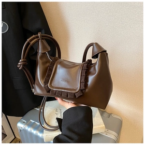 Close-up of brown leather crossbody bag with pleated ruffle flap and embossed logo