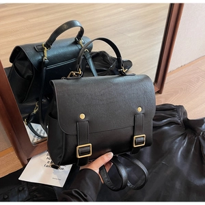 Detail of vintage black leather backpack featuring gold buckle and rivet accents