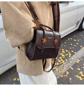 Detail of dark brown retro PU leather backpack with gold star buckles on street
