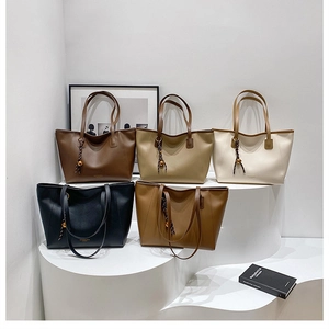 Dettaglio di grandi borse tote in pelle opaca in cinque colori con ciondoli intrecciati