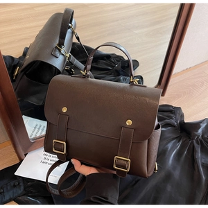 Detail of vintage dark brown PU leather backpack with gold metal buckles and top handle