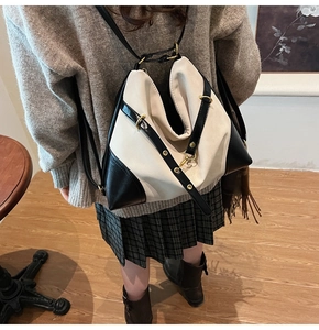 Detail of contrast stitch canvas backpack with black straps and golden metal hardware