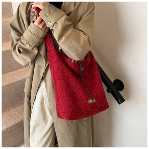 Détail du cabas en polaire rouge avec logo en cuir marron et doublure à carreaux