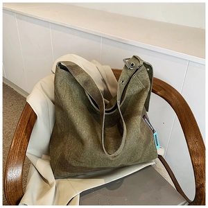 Detail of army green canvas tote bag with metal buckle on a stylish wooden chair
