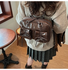 Detailed view of brown PU leather backpack with decorative ribbons and bow pockets