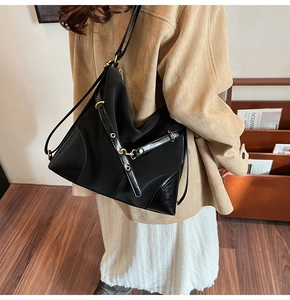 Close-up of large black nylon and leather bag with gold hardware worn by model