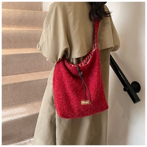 Détail du cabas en peluche rouge avec cordon de serrage et étiquette sur un mannequin