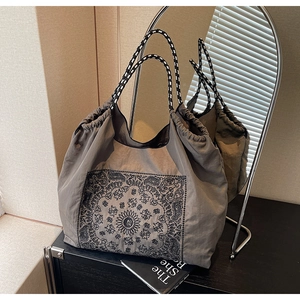 Mirror reflection showing ethnic print tote bag with woven handles and drawstring detail