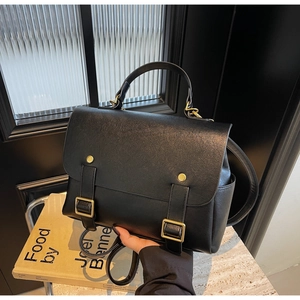 Close-up of black retro PU leather handbag with gold buckles and detachable strap
