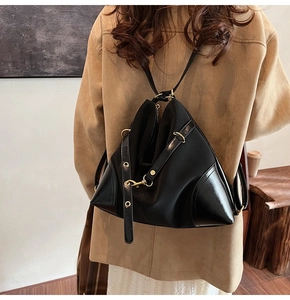 Detailed shot of modern black nylon backpack with leather trim and gold metal hooks