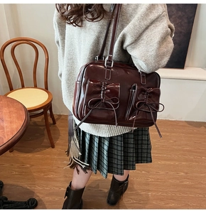 Detail of dark brown leather shoulder bag featuring white contrast stitching and bow pockets