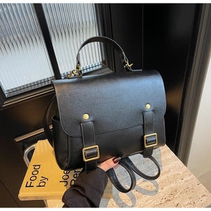Detail view of the black matte PU leather backpack with gold buckles and top handle