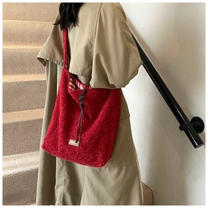 Détail du sac cabas en polaire rouge avec écusson en cuir et doublure à carreaux