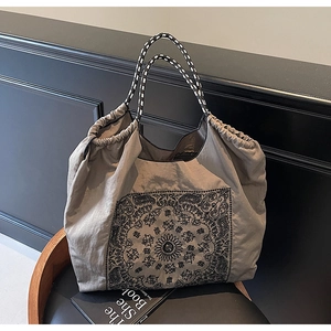 Close-up of vintage tote bag with mandala print and woven rope handles on wooden seat