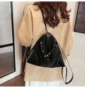 Back view of model wearing a black fabric and leather mix backpack with gold hardware