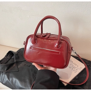 Detail view of a glossy red mini Boston bag with double zippers and sleek leather finish