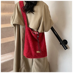 Détail du sac fourre-tout en peluche rouge avec cordon noir et doublure à damier