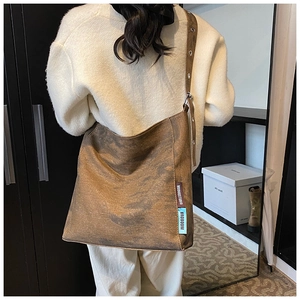 Detailed side view of brown canvas tote bag with decorative brand labels and wide strap