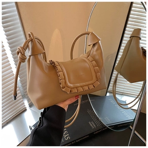 Detail of khaki leather shoulder bag featuring ruffled flap and elegant knotted strap
