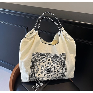 Detail of paisley pattern tote with woven handles on a vintage chair