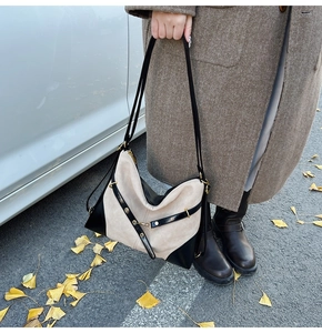 Detail of a large two-tone suede tote bag with black leather straps and gold metal buckles