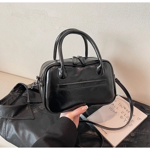 Detail of a vintage black glossy leather Boston bag with a convenient back zipper pocket